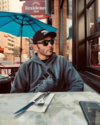 a man sitting at a table with an umbrella